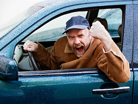 Furious male driver shakes his fist out of car window