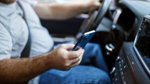 middle-aged caucasian man sitting in car, texting on smartphone