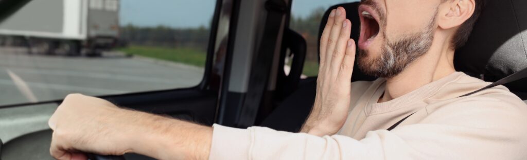 photo of a drowsy driver yawning while driving