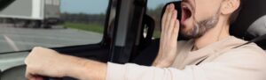 photo of a drowsy driver yawning while driving