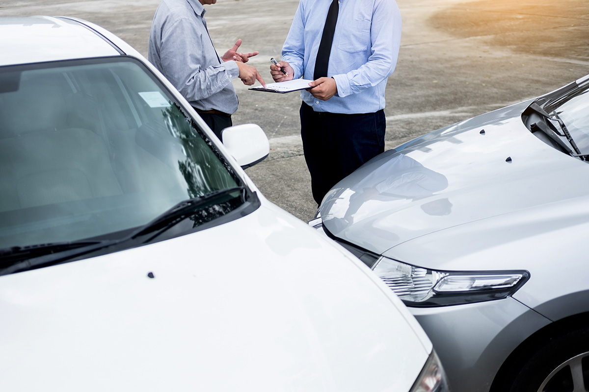 Insurance Agent Writing On Clipboard While Examining Car After A Insurance Agent Writing On Clipboard While Examining Car After A