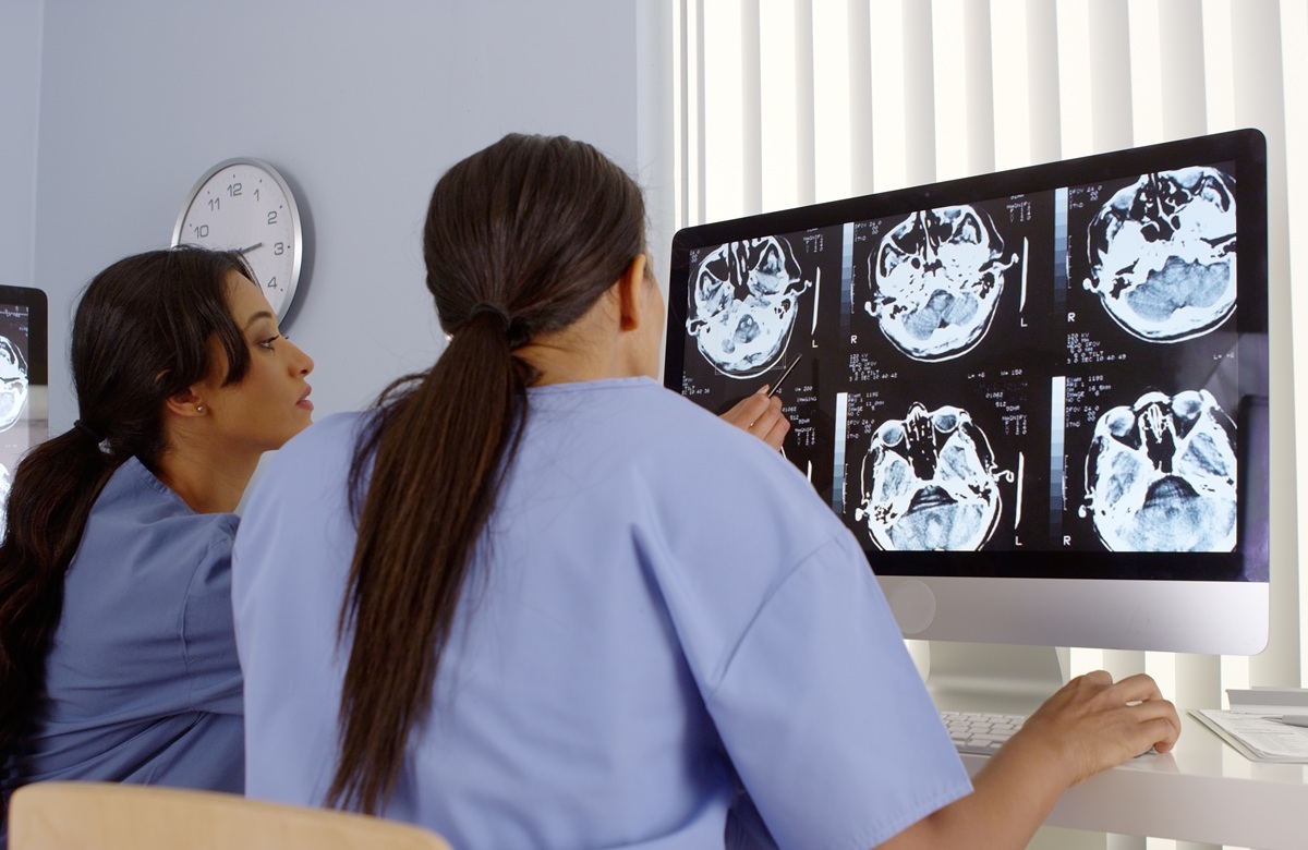 Rear View Of Two Female Doctors Working Together On Computers