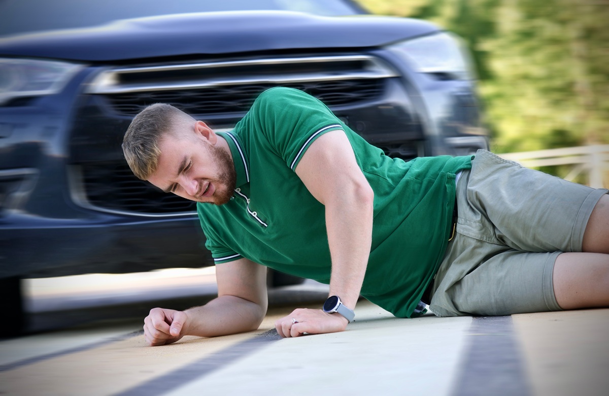 Young Downed Man At Accident Scene, Crash On The Road On Crosswalk. Pedestrian Guy Hit By Careless Driver In A Car On The Road While Crossing Highway, Person Is Lying On Asphalt. Dangerous Situation
